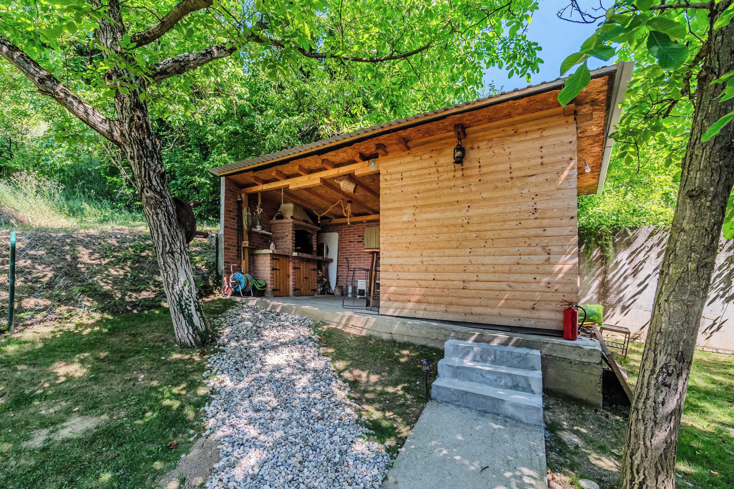 A wooden cabin with a brick fireplace, gravel path, and steps leading to the entrance.
