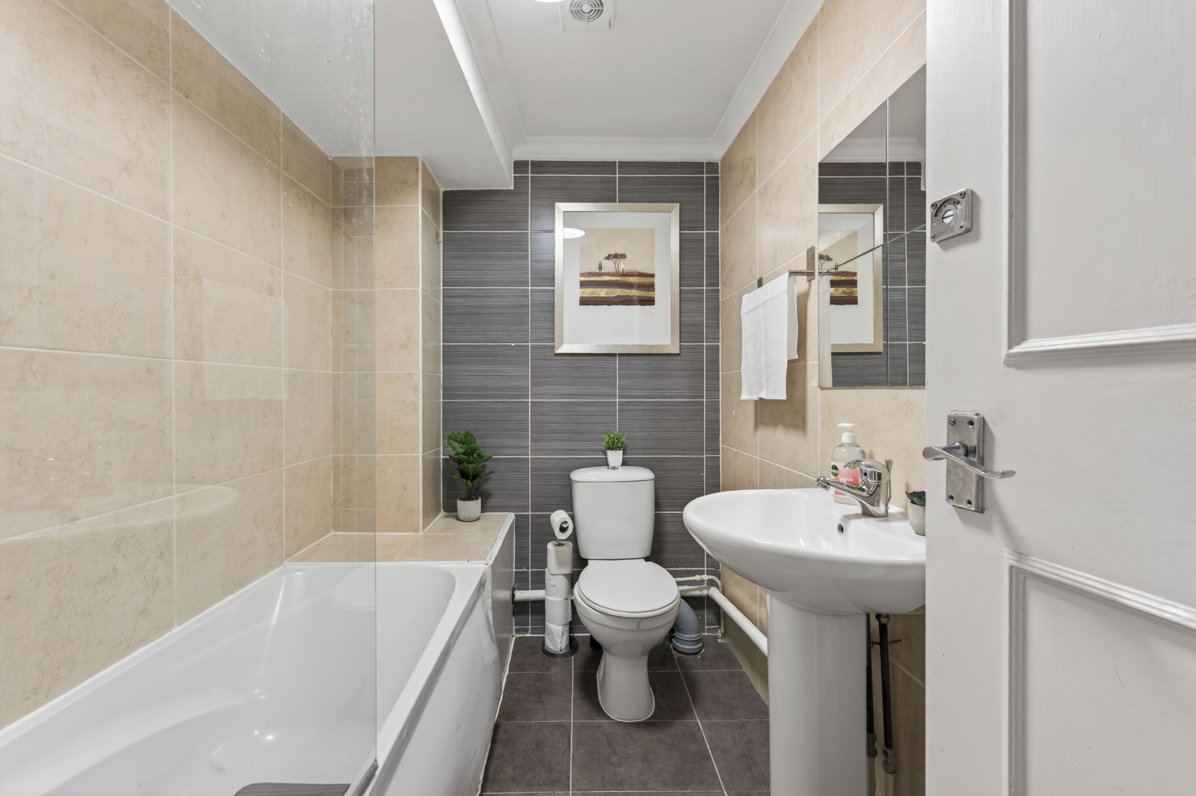 Un bagno moderno con vasca, servizi igienici, lavandino e un quadro appeso al muro.