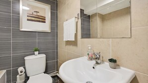 Ein Badezimmer mit Toilette, Waschbecken, Spiegel und einem gerahmten Bild an der Wand.