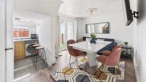 Eine moderne Küche mit Waschmaschine, ein Essbereich mit weißem Tisch und Stühlen sowie ein großes Spiegelbild an der Wand.