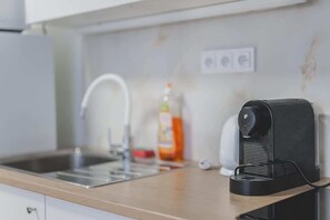 Une cuisine équipée d’un évier, d’une machine à café et d’une bouteille de liquide vaisselle.