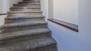 Un escalier avec une rampe en bois et un mur blanc orné d’une fenêtre.