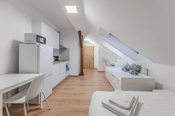 Une pièce de taille modeste comprenant un coin cuisine, un lit et un bureau.