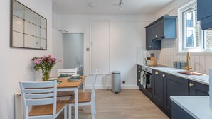 Una cocina moderna con armarios blancos, una mesa de comedor con sillas y una ventana con vistas.