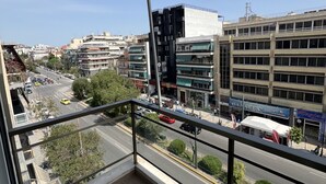 Un balcón con vistas a un paisaje urbano, que incluye edificios y una carretera.