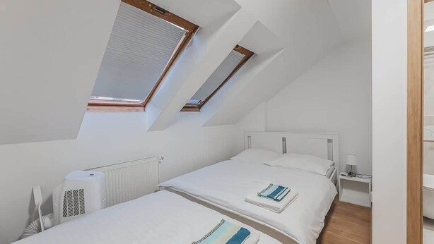 A room with two beds, a radiator, a window, and a wooden door. - Andel, Smichov Flat, Fresh Bath, port AC, Kitchen (Praha 5)