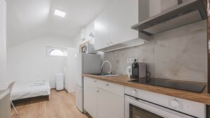A compact kitchen with a built-in oven, a coffee maker, and a window. - Andel,Smichov Flat, Fresh Bath, portable AC (Praha 5)