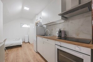 Eine kleine Küche mit integriertem Backofen, einer Kaffeemaschine und einem Fenster.