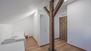 Ein Schlafzimmer mit Bett, Kleiderschrank und Holzbalken.