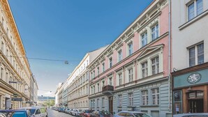 Eine Straße mit historischen Gebäuden, parkenden Autos und blauem Himmel.