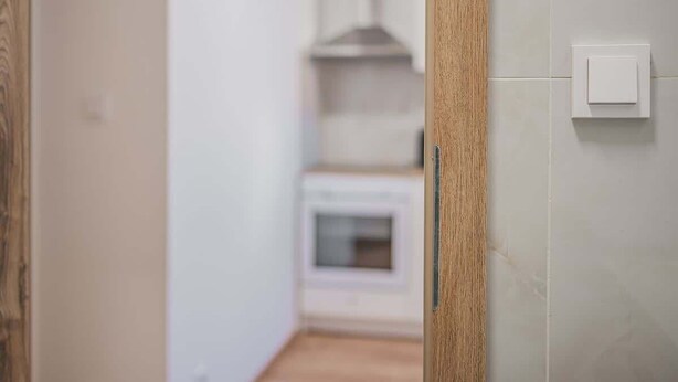 Un corridoio che porta a una cucina con un forno bianco e una cappa aspirante.