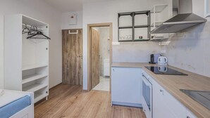Una cucina compatta con forno a incasso, microonde e macchina del caffè sul piano di lavoro.