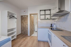 Eine kompakte Küche mit einbauendem Backofen, einer Mikrowelle und einer Kaffeemaschine auf der Arbeitsfläche.