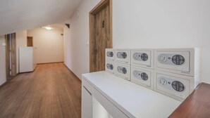 Una lavanderia con diverse lavatrici e asciugatrici, una porta in legno e un corridoio.