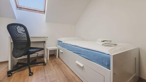 Una camera in stile dormitorio con un letto, una scrivania e una sedia.