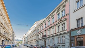 Katu, jonka varrella on historiallisia rakennuksia, parkkeerattuja autoja ja kirkas taivas.
