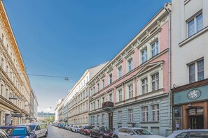 Eine Straße mit historischen Gebäuden, parkenden Autos und blauem Himmel.