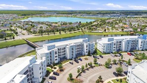 Un immeuble d’appartements moderne doté d’une cour intérieure, d’un espace de stationnement et d’un lac en arrière-plan.