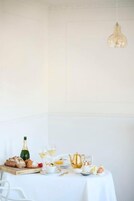 A table set with a bottle, glasses, a teapot, and bread.