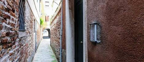 A narrow alleyway with brick walls and a door on the right.