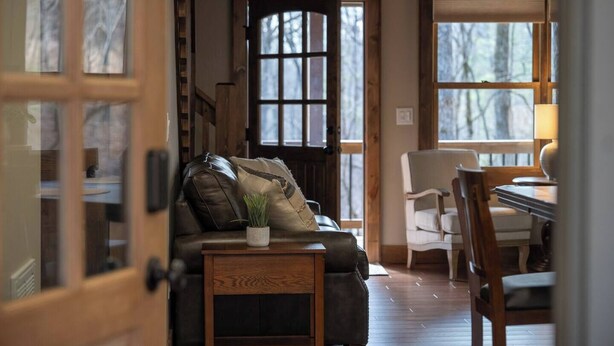 A cozy living room with a leather sofa, a small wooden table, and a white chair. - Thyme Out | Hot Tub | 7 Minutes to Blue Ridge (Blue Ridge)