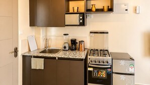 A modern kitchen with a gas stove, microwave, and oven, a coffee maker, and a blender on the counter. - Beautiful Place to Unwind – Executive Studio at Garden City Mall, Garden 237 (Nairobi)