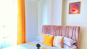 A neatly made bed with a headboard, a small plant on the bed, and a brown rug on the floor. - Beautiful Place to Unwind – Executive Studio at Garden City Mall, Garden 237 (Nairobi)