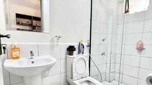 A modern bathroom with a sink, toilet, and shower. - Beautiful Place to Unwind – Executive Studio at Garden City Mall, Garden 237 (Nairobi)