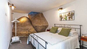 Ein Schlafzimmer mit einem Bett, einer großen Felsformation, Wandkunst und einem Metallbettgestell.