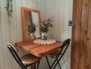 Ein Holztisch mit zwei Stühlen, eine Vase mit Blumen und ein Spiegel an der Wand.