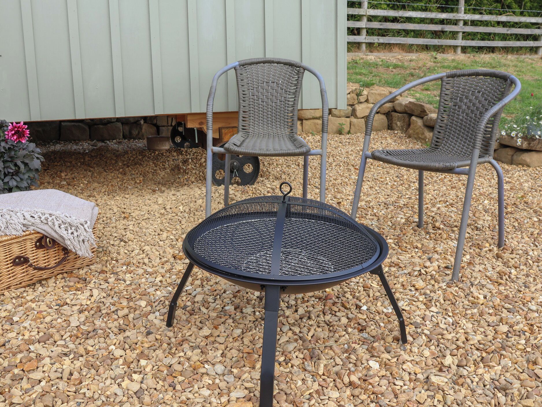 A round outdoor table with a metal frame and a woven chair with a metal frame.