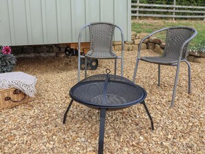 A round outdoor table with a metal frame and a woven chair with a metal frame. - Thistlewoods Shepherds Hut (Whitby)