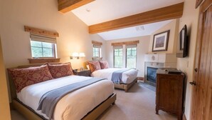 A bedroom with two beds, a fireplace, and wooden beams on the ceiling. - One Bedroom Two Queen Suite 1 Suite (Park City)