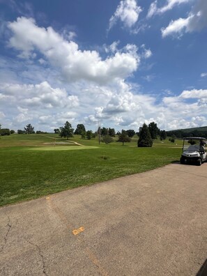 Un campo da golf con cielo sereno, erba verde e un carrello da golf.
