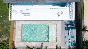 An aerial view of a rooftop with a swimming pool, lounge chairs, and a covered seating area. - New 5br Remodel, Heated Pool, Gameroom, Up To 20 4 Bedroom Home (South Padre Island)