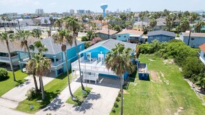 A residential area with houses, palm trees, and a water tower in the background. - New 5br Remodel, Heated Pool, Gameroom, Up To 20 4 Bedroom Home (South Padre Island)