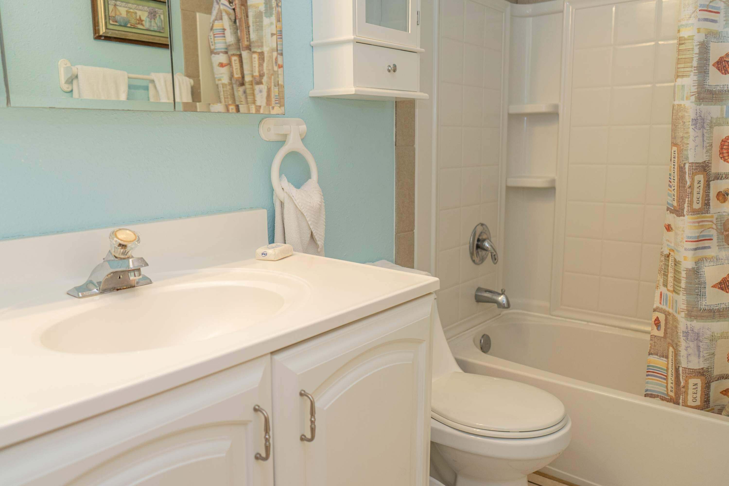 Une salle de bain avec un lavabo, des toilettes et une baignoire, le tout de couleur blanche.