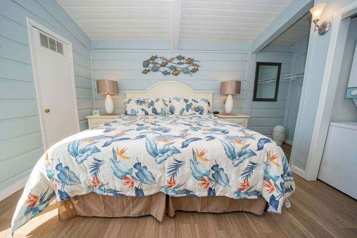A bedroom with a bed, two bedside lamps, a wall-mounted light fixture, and a decorative wall piece.
