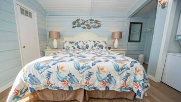 A bedroom with a bed, two bedside lamps, a wall-mounted light fixture, and a decorative wall piece.