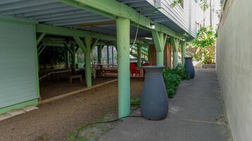 A covered outdoor area with a bench, a large planter, and a pathway.
