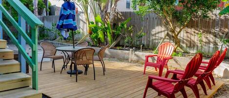 Una terraza de madera con mobiliario exterior, una mesa y sillas.