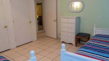 A bedroom with two beds, a dresser, a mirror, and a door leading to another room.