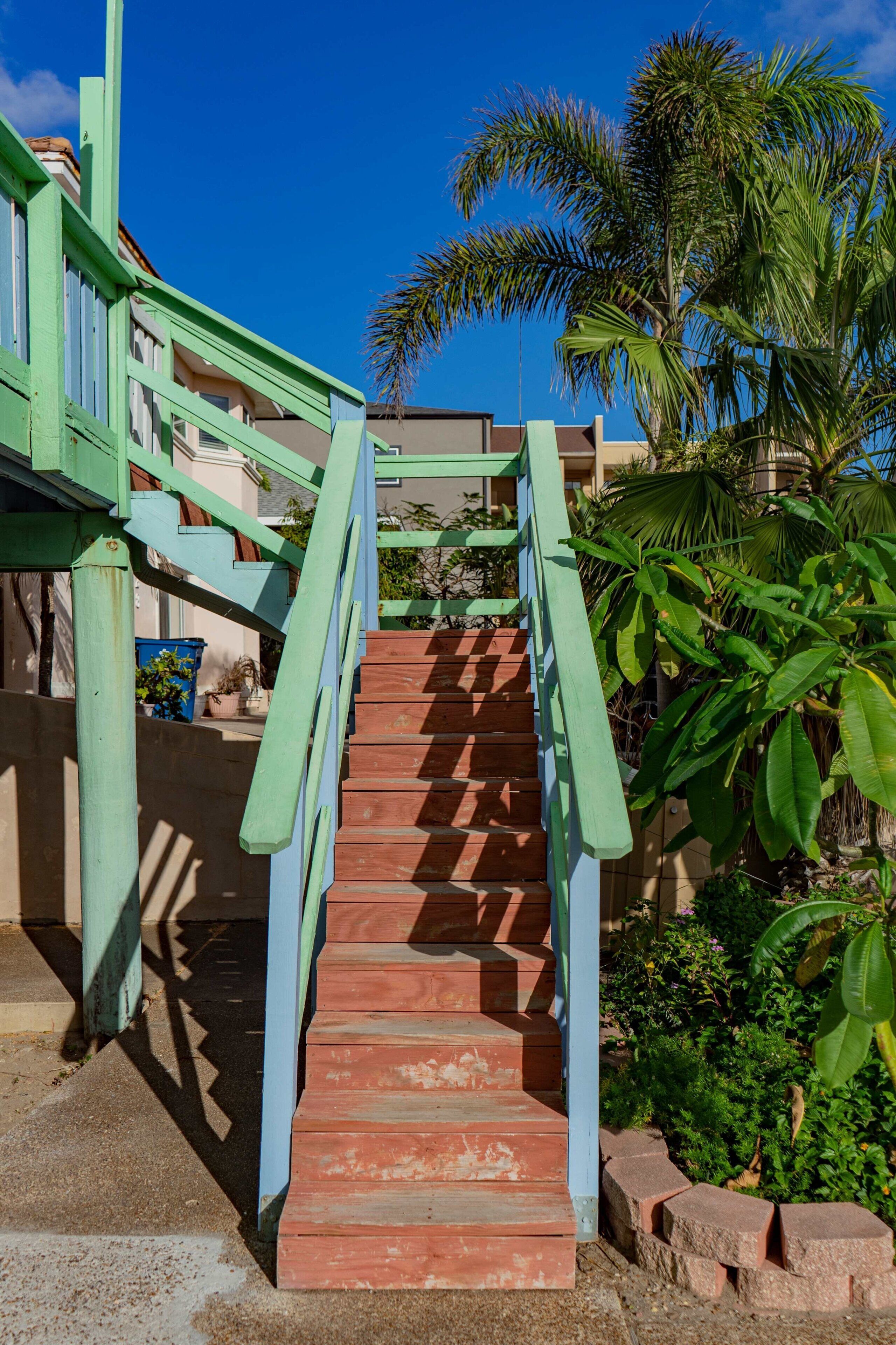 A staircase with green railings leading to a building with a red roof.