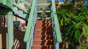A staircase with green railings leading to a building with a red roof.