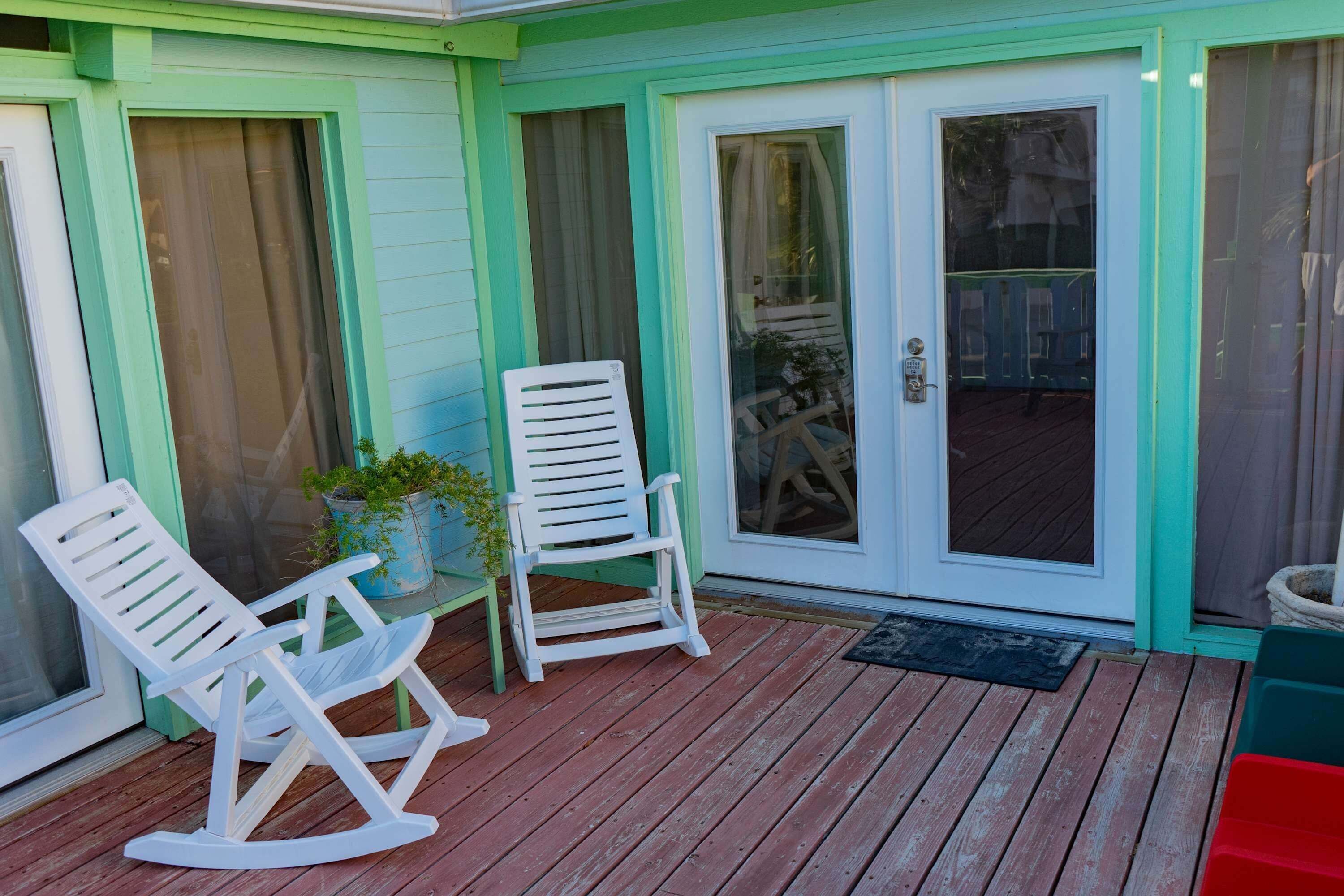 A wooden deck with two rocking chairs and a potted plant.