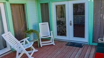 A wooden deck with two rocking chairs and a potted plant.