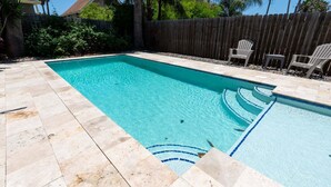 Une piscine rectangulaire à l’eau d’un bleu limpide, entourée d’une terrasse carrelée.