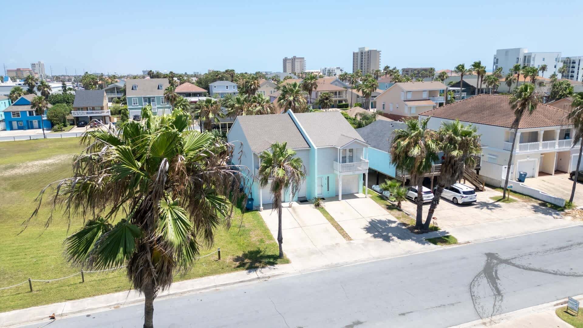 A residential area with houses, palm trees, and a clear sky.