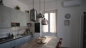 Una cuina moderna amb una illa de fusta, llums penjants i vista a l'exterior.