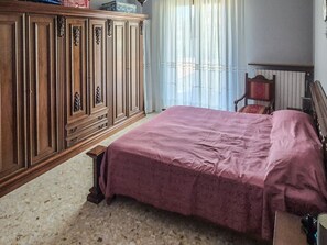 Una camera da letto con un letto, un armadio in legno e una sedia.